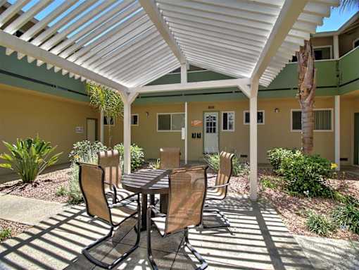 A patio with a table and chairs is covered by a white roof.