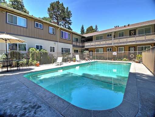 A swimming pool in a residential area surrounded by a fence.