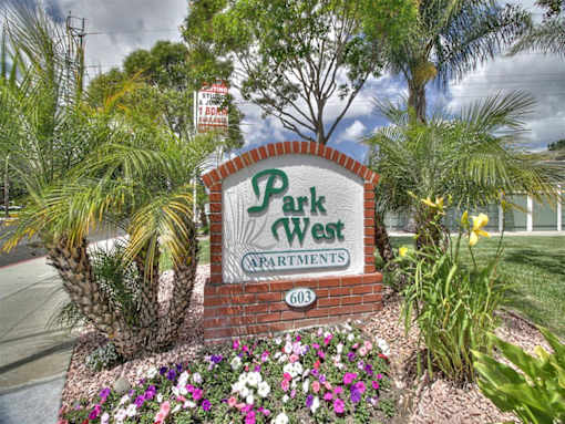 A sign for Park West Carra Rentments with flowers in front.