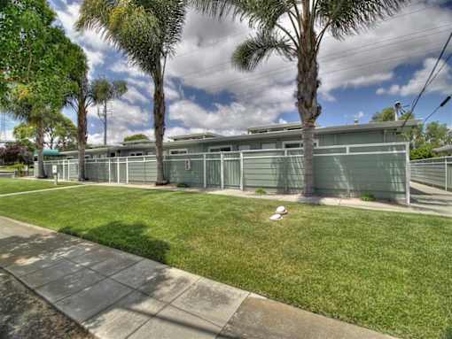 A row of green garages are lined up on a sidewalk.