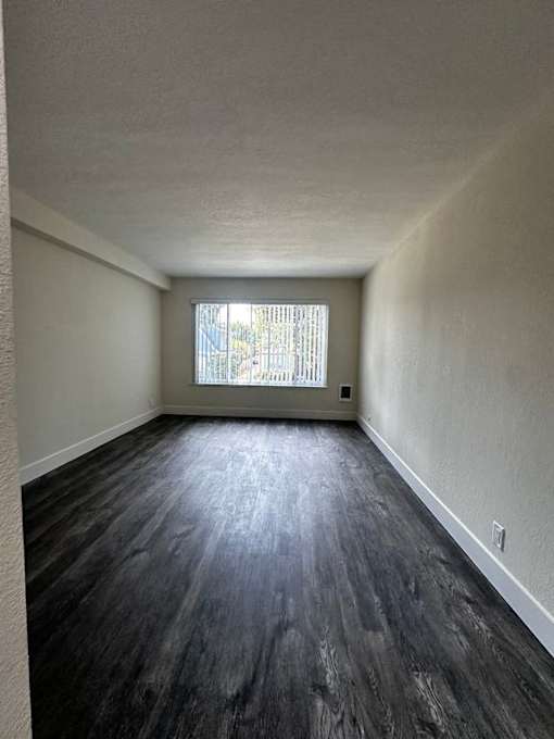 an empty room with wood floors and a window