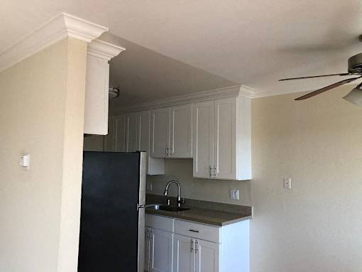 a kitchen with a black refrigerator and white cabinets