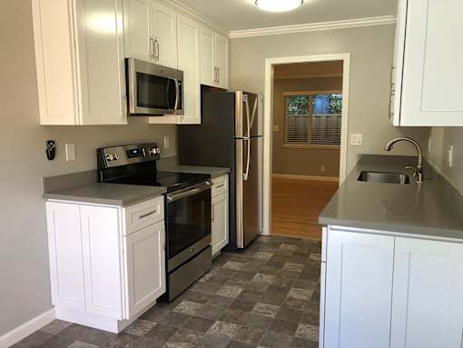 A kitchen with white cabinets and a black refrigerator.