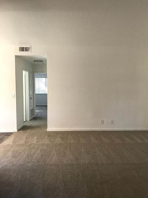 A room with a carpeted floor and a doorway leading to another room.