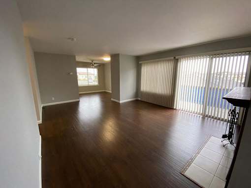 an empty living room with wood flooring and sliding glass doors