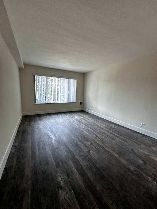 an empty living room with wooden floors and a window