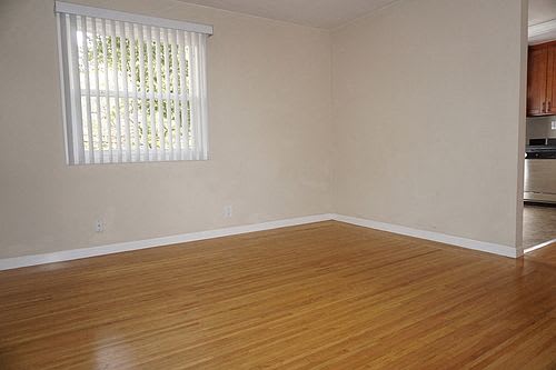 A room with wooden floors and a window with blinds.