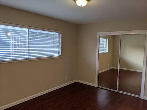 A room with a sliding glass door and a window with blinds.