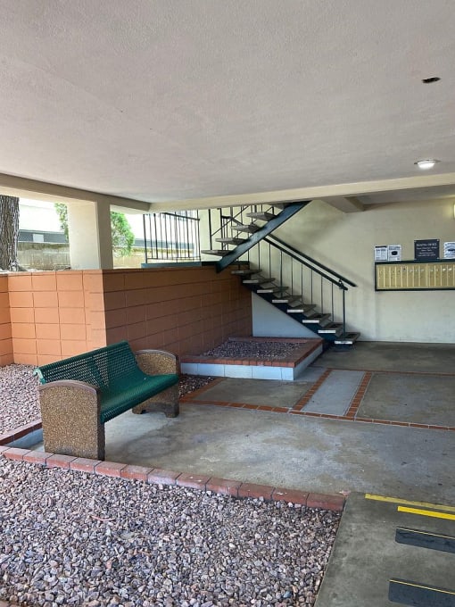 A green bench sits in front of a staircase.
