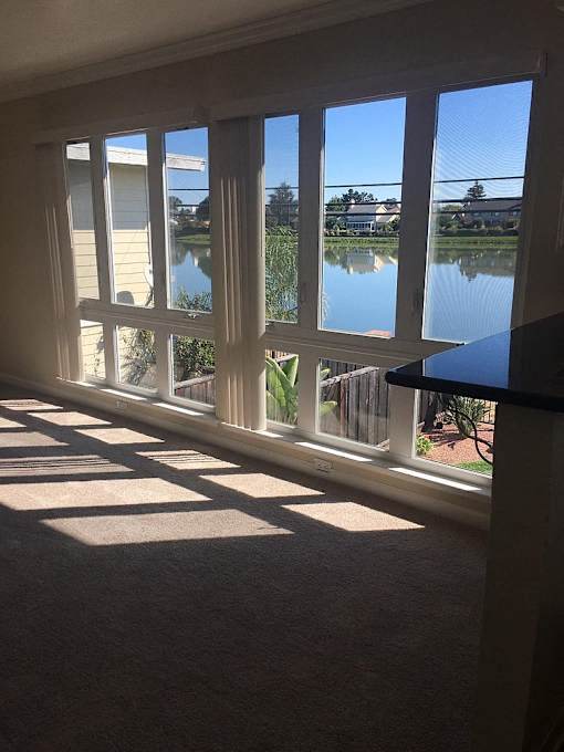 a living room with many windows and a view of a lake