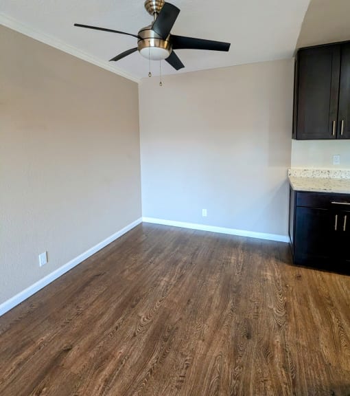 an empty living room with wooden floors and a ceiling fan