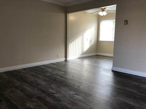 an empty living room with wood floors and a ceiling fan
