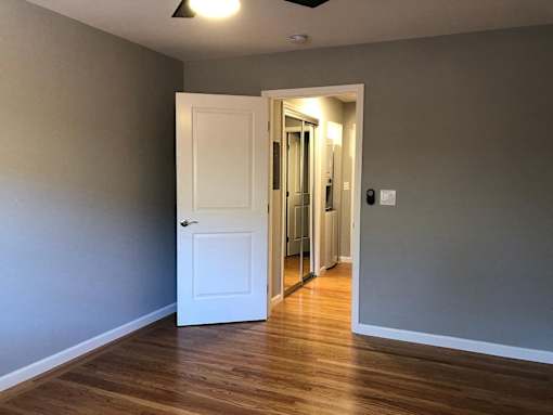 A room with a white door and wooden floor.