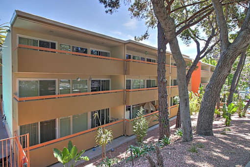 A building with orange and beige colors surrounded by trees.