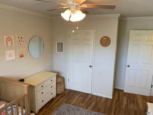 a nursery with a crib and a ceiling fan