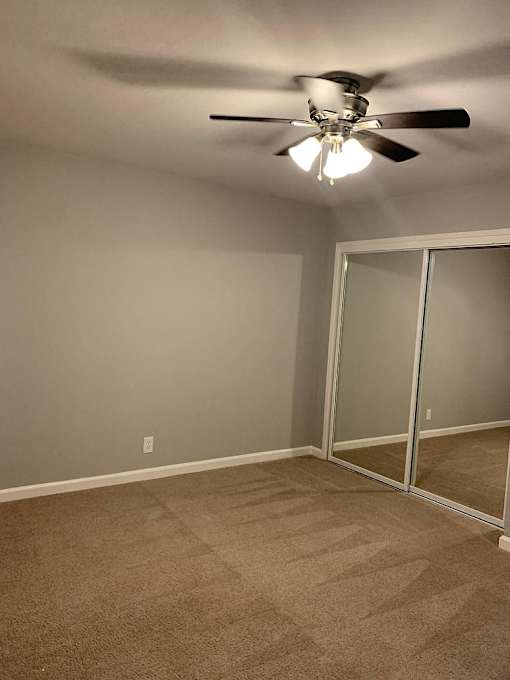 A room with a ceiling fan and a glass door.