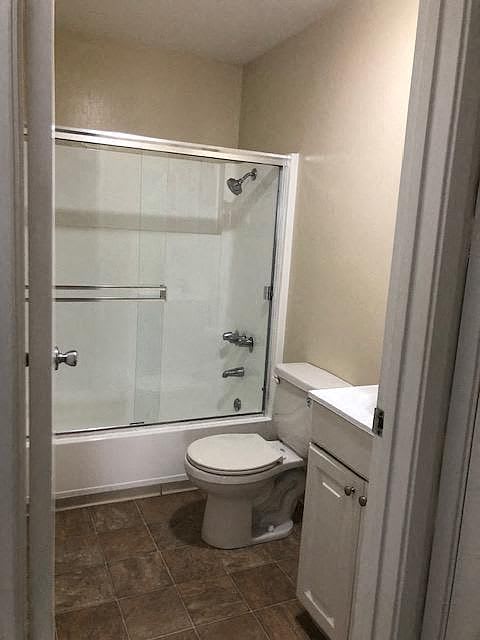 A white toilet sits in a bathroom next to a glass shower door.