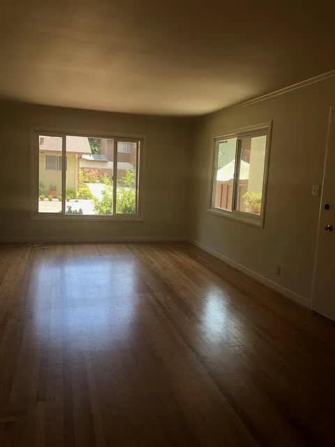 A room with wooden floors and two windows.