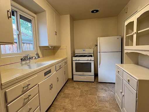 A kitchen with white appliances and cabinets.