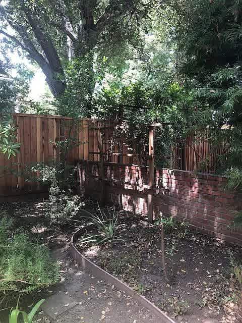 A garden with a wooden fence and a brick wall.