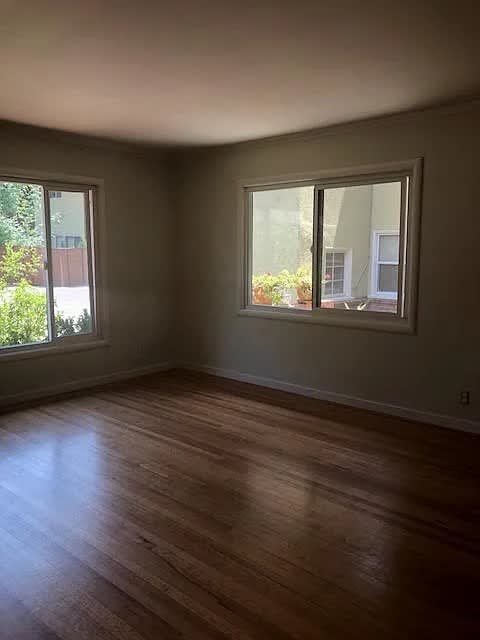 A room with wooden floors and two windows.