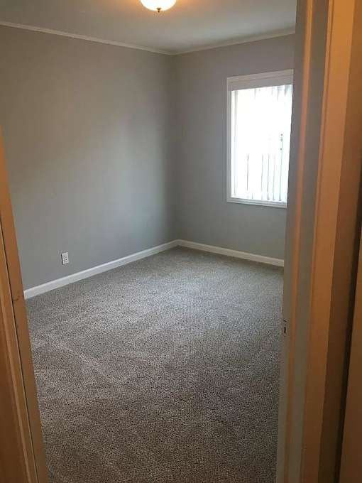 A room with a carpeted floor and a window.