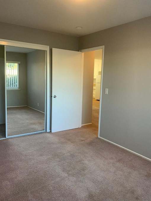 A room with a carpeted floor and a white door.