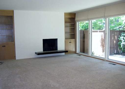 A living room with a flat screen TV and sliding glass doors.