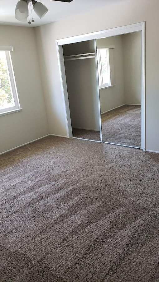 A room with a carpeted floor and a ceiling fan.