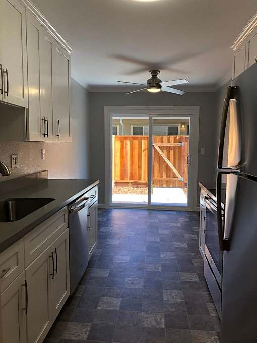 A kitchen with a checkered floor and a ceiling fan.