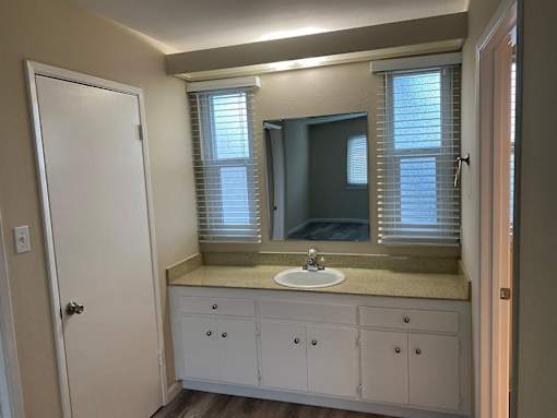 A bathroom with a sink, mirror, and cabinets.