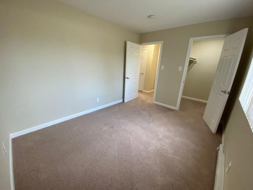 a bedroom with a carpeted floor and a door to a closet