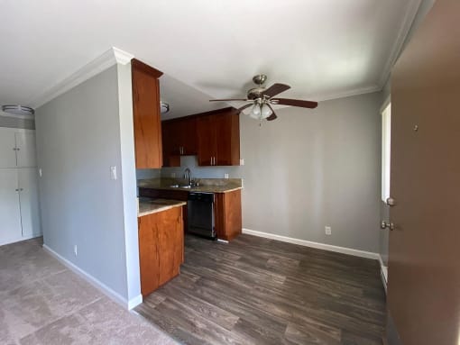 a empty kitchen with a ceiling fan and wooden floors