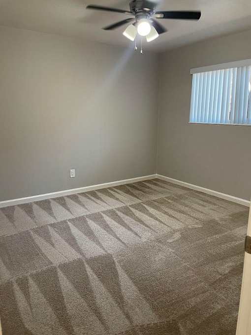 A room with a ceiling fan and carpeted floor.