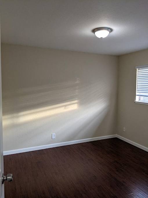 A room with a wooden floor and a door on the left side.