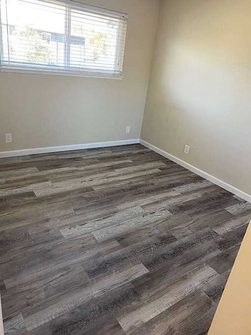 A room with a wooden floor and a window with blinds.