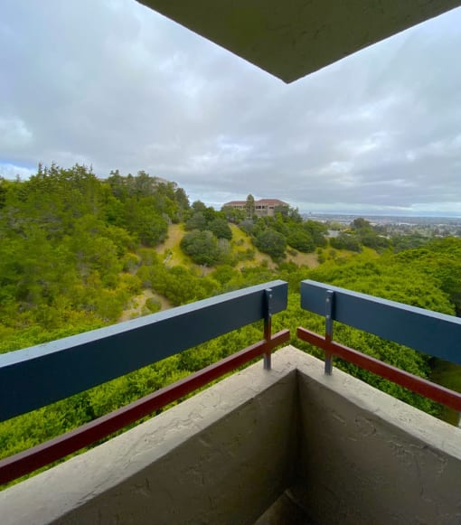 a balcony with a view of trees and a building in the distance