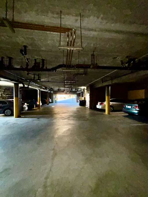A long, narrow parking garage with cars parked on both sides.