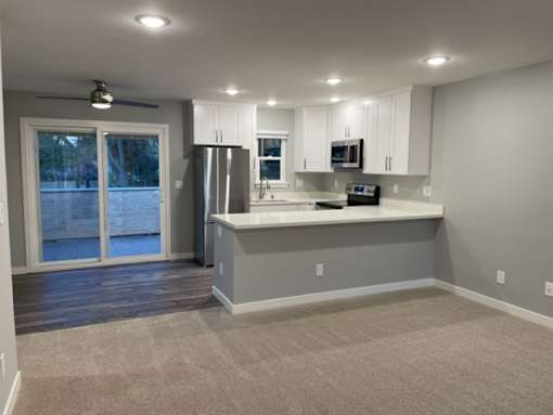 A kitchen with white cabinets and a grey island.