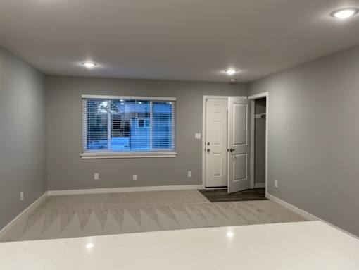 A room with a white floor and a window with blinds.