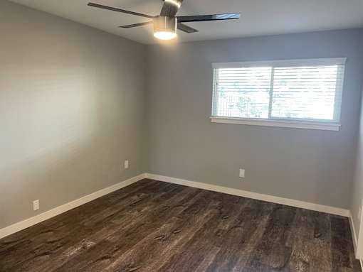 A room with a ceiling fan and a window with blinds.