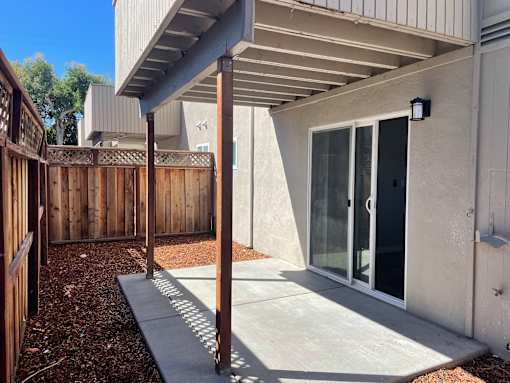 A patio area with a concrete floor and a wooden fence.