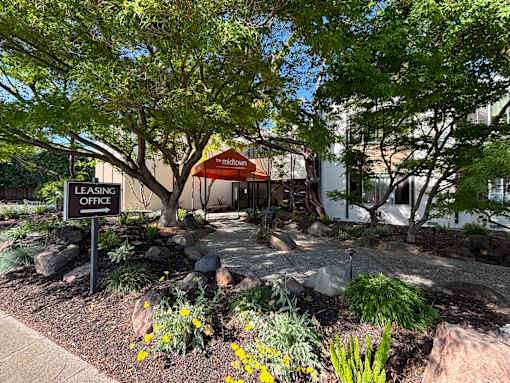 A leasing office is surrounded by trees and plants.