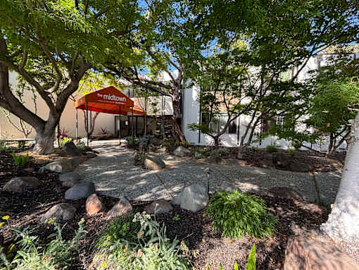 A tree-filled area with a tent and a sign that says "The Midtown".