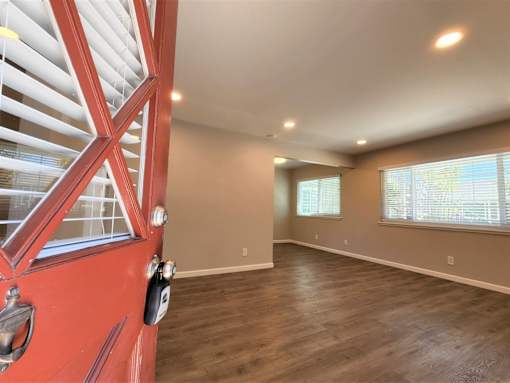 A room with a red door and wooden flooring.