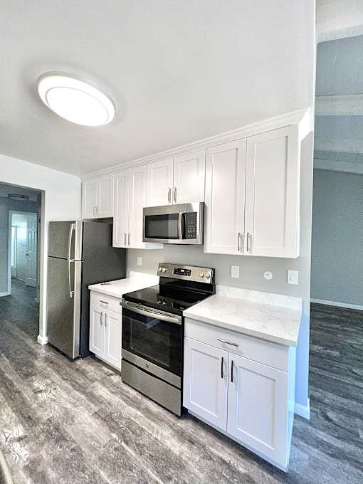a small kitchen with white cabinets and stainless steel appliances