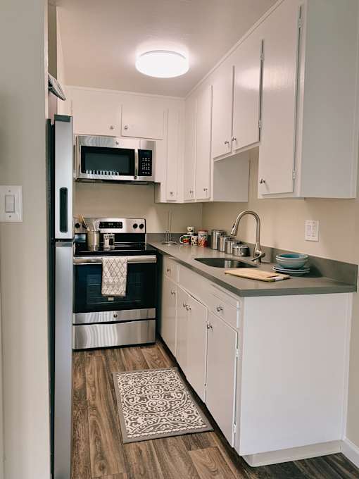 a small kitchen with white cabinets and black appliances