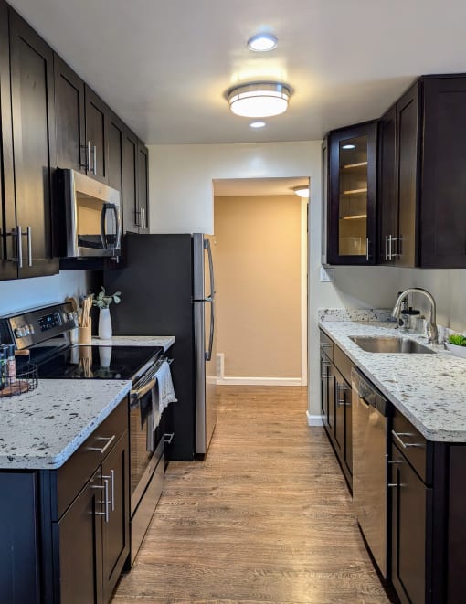 a kitchen with black cabinets and granite counter tops and a stainless steel refrigerator