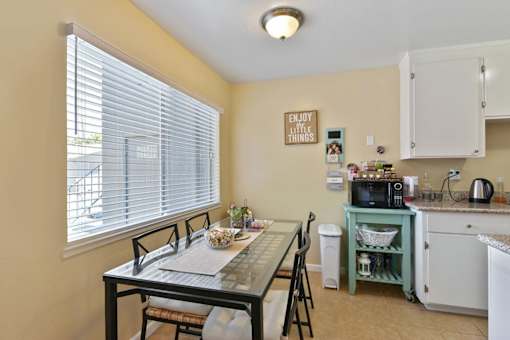 A kitchen with a table and chairs by a window.