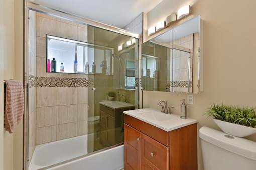 A bathroom with a white sink and a glass shower door.